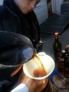 Pouring the Manhattan ingredients into the barrel through a funnel.